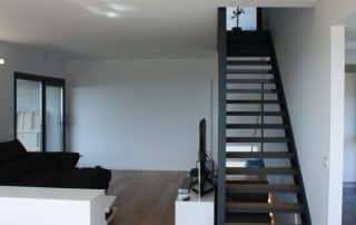 02-casa-prefabricada-hormigon-sala estar-01 Escalera y sala de estar con grandes ventanales
