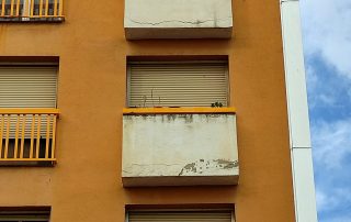 Balcony fronts with spalling and deteriorated render before the retrofit