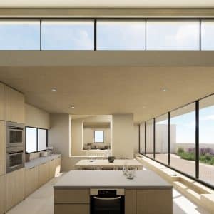 Vista de la cocina con isla y sala de estar y escalera de fondo. Gran ventanal a jardín terraza